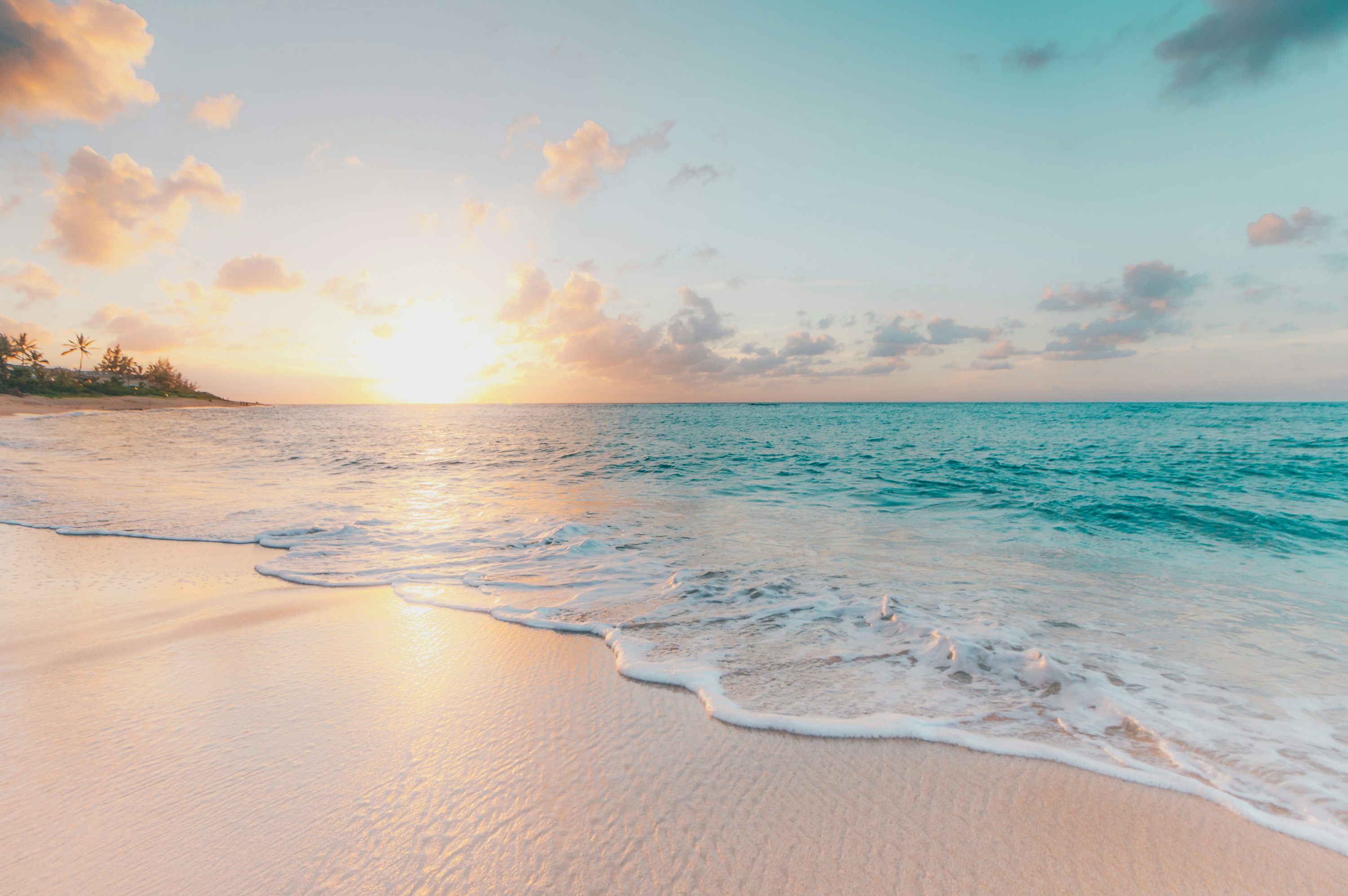 Serene tropical beach at sunset with golden sky and gentle waves