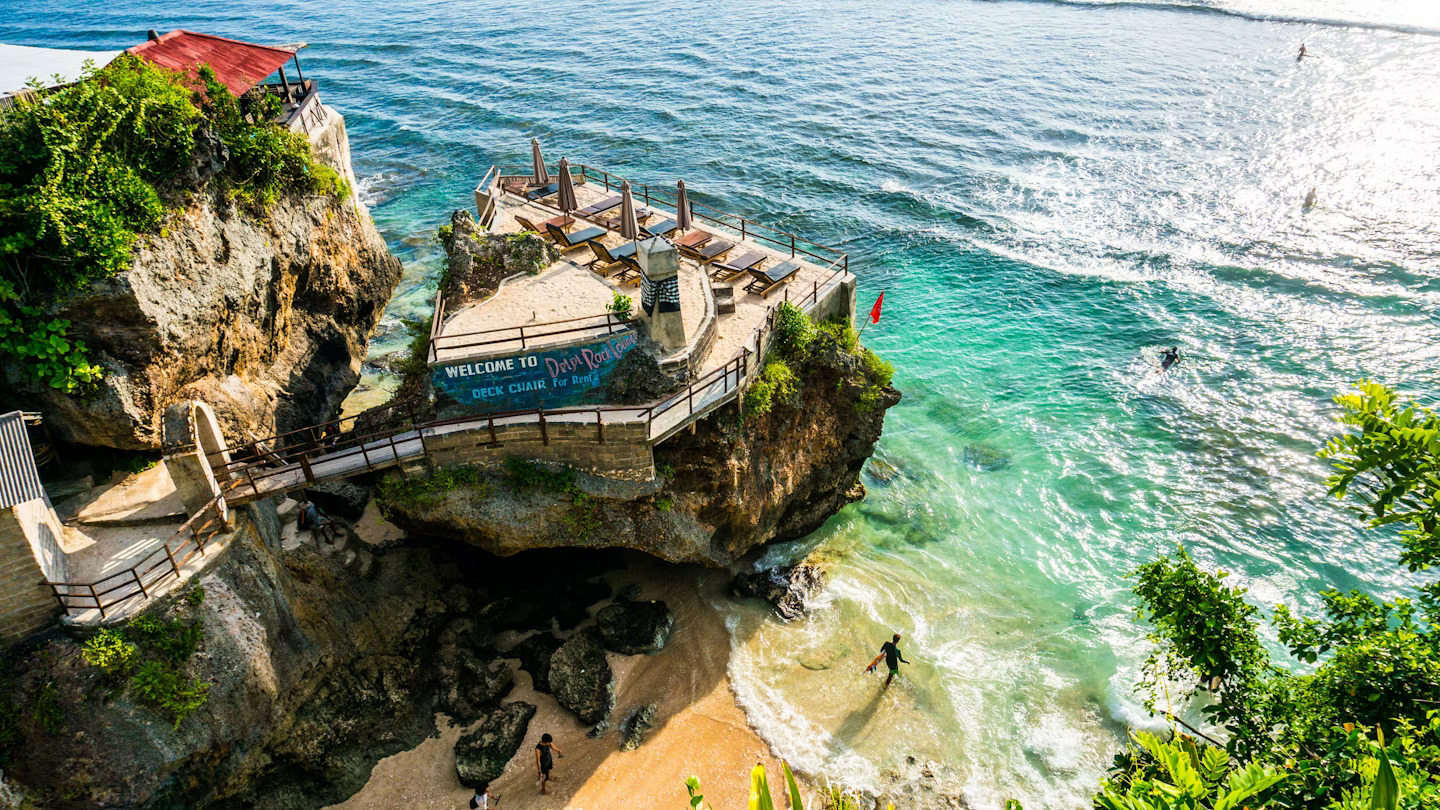 Dramatic Bali clifftop restaurant overlooking turquoise waters with Welcome to Bali sign